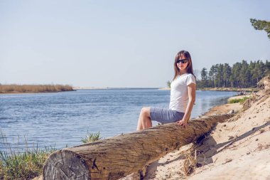 Deniz kıyısında yatan gülümseyen genç kadının portresi