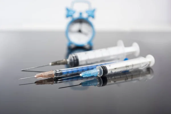 Czas szczepienia. Szczepionka w fiolce ze strzykawką na tle zegara. Profilaktyka immunizacji choroby. — Zdjęcie stockowe