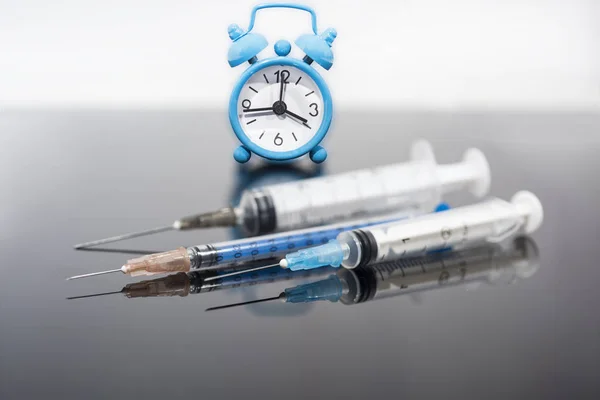 Vaccinations tid. Vaccin i injektions flaska med spruta på klock bakgrund. Förebyggande immuniseringssjukdom. — Stockfoto