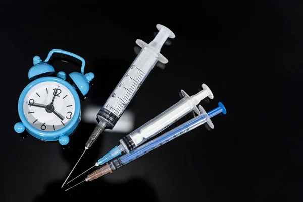 Impfzeit. Impfstoff in Fläschchen mit Spritze auf dem Hintergrund der Uhr. Prävention von Immunisierungskrankheiten. — Stockfoto