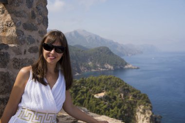 Cap de Formentor, Mallorca, İspanya. Deniz, kayalar ve bulutlu gökyüzü ile güzel sahne önünde Genç kadın.