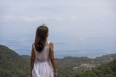 Cap de Formentor, Mallorca, İspanya. Deniz, kayalar ve bulutlu gökyüzü ile güzel sahne önünde Genç kadın.