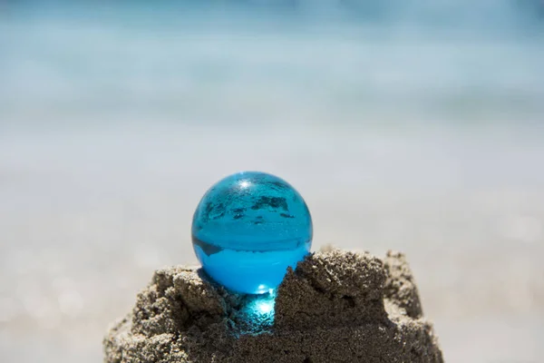 Glass sphere at the beach. Sunny summer day. Abstract photo of summer vacation days.