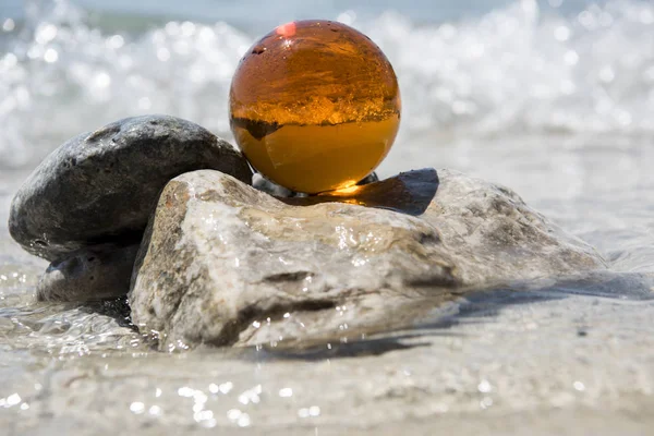 Glass sphere at the beach. Sunny summer day. Abstract photo of summer vacation days.