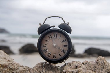 Okyanus tarafından gün doğumunda bir kaya üzerinde çalar saat