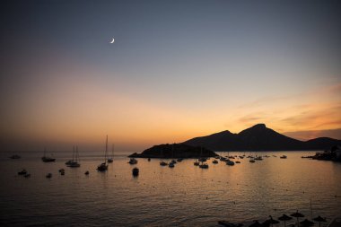 Sant Elm şehrinden Mallorca 'daki Ejderha Adası' na doğru günbatımı görüntüsü. Ayla kararmış gökyüzü.