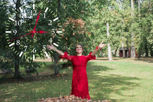 Junge Frau in rotem Kleid. werfen die Herbstblätter nach oben. — Stockfoto