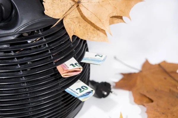 Money for heating bills with black heater on white background. Autumn season.