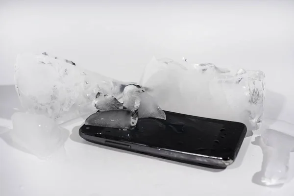 氷でフリーズの黒いスマート フォン。抽象オブジェクトの写真. — ストック写真