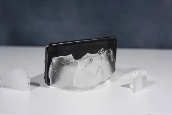 Чорний смартфон заморожений у льоду. Абстрактне фото об'єкта . — стокове фото