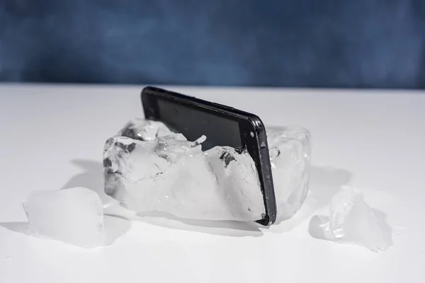 Smartphone negro congelado en hielo. Objeto abstracto foto . — Foto de Stock