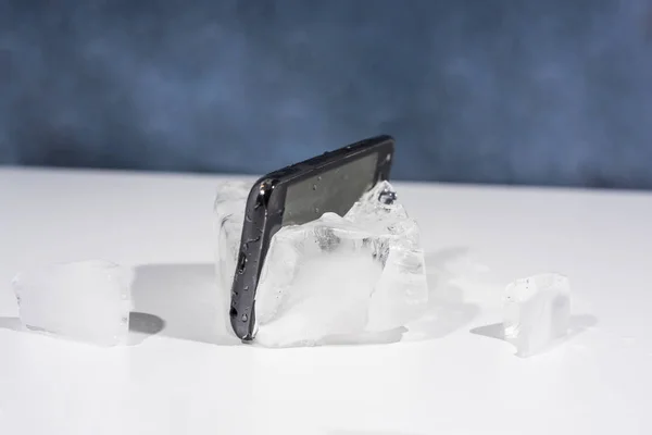 Černý smartphone zamrzlé v ledu. Abstraktní objekt Foto. — Stock fotografie