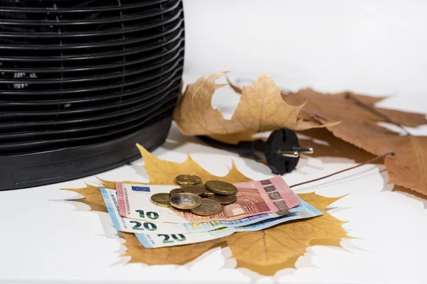 Money for heating bills with black heater on white background. Autumn season.