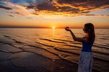 Güzel genç kadın gün batımında dinleniyor.
