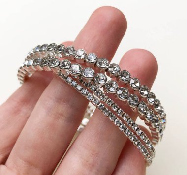 Beyaz bir arka planda, elinde elmaslar olan bilezik..