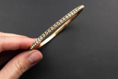 Ellerinde elmaslar olan bilezik koyu arkaplanda..