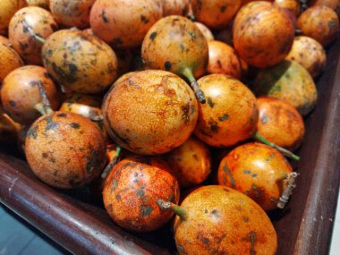 Yerel bir markette tahta bir sandıkta olgunlaşmış bir tutku meyvesi yığını.