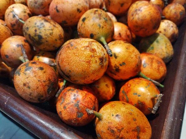 Yerel bir markette tahta bir sandıkta olgunlaşmış bir tutku meyvesi yığını.