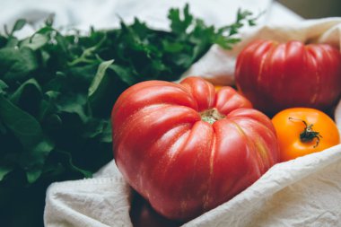 Yeniden kullanılabilir çevre dostu bez torbaları kırmızı ve sarı domates ve yeşillik ile. Yerel pazar sebze. Çiftçilerin ürünleri. Filtre uygulanan görüntü işleme
