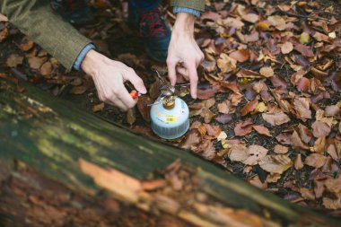 Male hands setup and operate canister stove. Hiking in the autumn forest with backpacking stove clipart