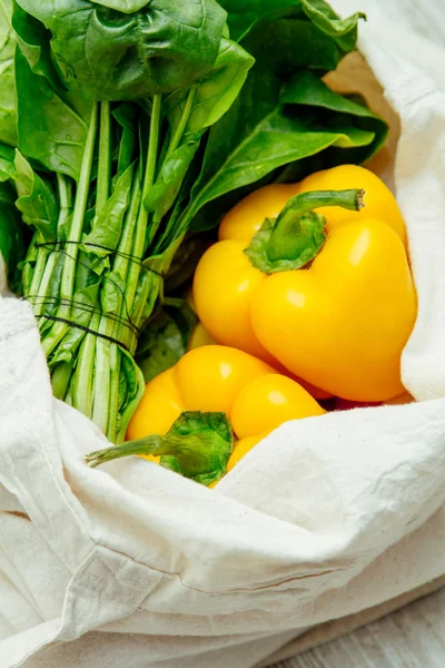 Ispanak ve mutfak masasının üzerinde yeniden kullanılabilir çanta içinde tatlı biber. Daha az plastik bakkal kavramı