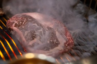 Wagyu beef on a flame grill cooking at a Korean BBQ