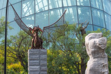 Heykel metal, bahçeleri tarafından Bay bir ejderha. Demir ejderha heykelin arka plan cam bir duvar üzerinde bir taş kaide üzerine