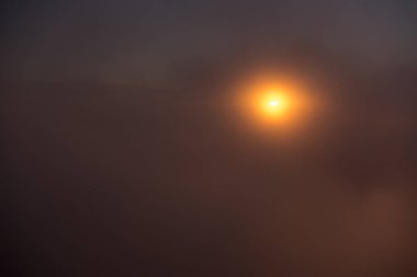 Puslu gökyüzünde turuncu günbatımı