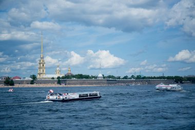 Nehir kıyısında mavi gökyüzünün altında şehir binaları arasında bir güvertesi olan bir eğlence teknesi.