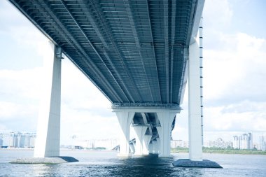 Mavi gökyüzüne karşı nehrin üzerindeki gri yol köprüsü