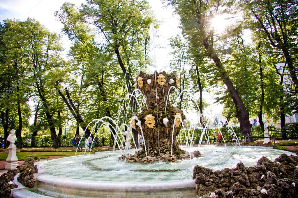 vintage fountain with water jets in the park on a background of trees