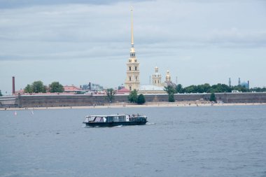 Nehir kıyısında mavi gökyüzünün altında şehir binaları arasında bir güvertesi olan bir eğlence teknesi.