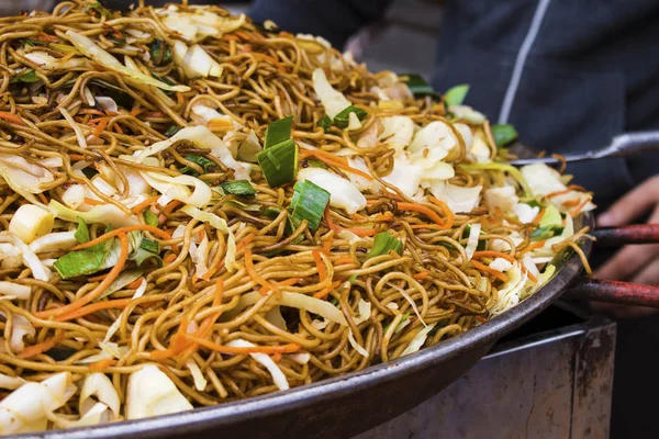 Fideos chinos asiáticos en una sartén wok en el mercado callejero de alimentos — Foto de Stock