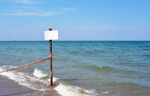 Weiße Tafel auf Holzstange, Meer auf Hintergrund — Stockfoto