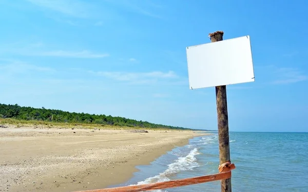 Ahşap direk üzerinde boş beyaz tahta, arka planda deniz — Stok fotoğraf