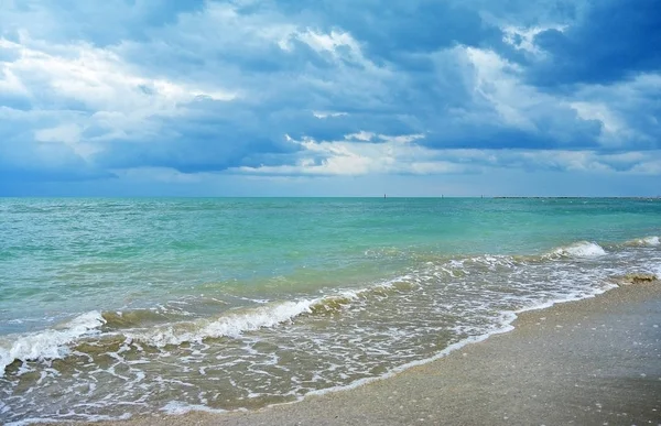 Donkere regenwolken over de turquoise zee en zandstrand — Stockfoto