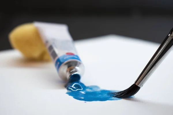 Blaue Ölfarbe, Tube und Pinsel auf weißem Papier — Stockfoto