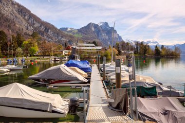 Walensee Gölü'ndeki ahşap iskelede brandayla kaplı tekneler. Weesen, İsviçre.