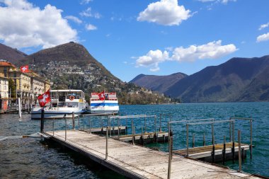 Lugano, SWitzerland - 17 Nisan 2018. Lugano Gölü 'ndeki Lugano şehri Alplerle çevrilidir. Rıhtımdaki zevk aracının görüntüsü. Lugano, Ticino kantonu, İsviçre, Avrupa.