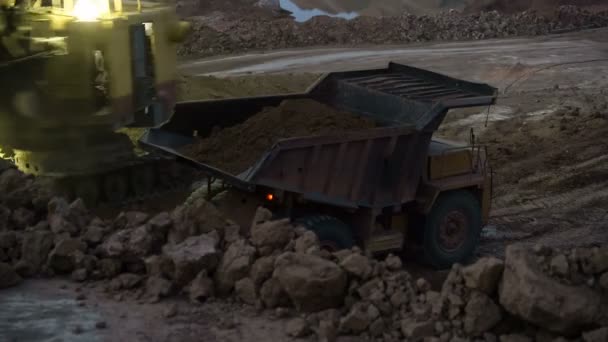 Caducidad del mineral de carga de la excavadora en camiones volquete al atardecer . — Vídeo de stock