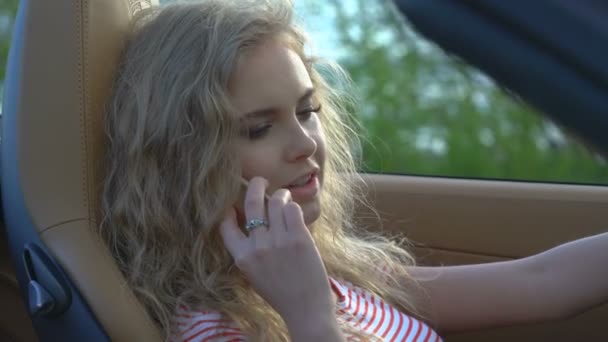 Νέοι όμορφη ξανθιά γυναίκα, μιλώντας στο τηλέφωνό της στο αυτοκίνητό της ολοκαίνουργιο μοντέρνο εσωτερικό με δερμάτινα καθίσματα. — Αρχείο Βίντεο
