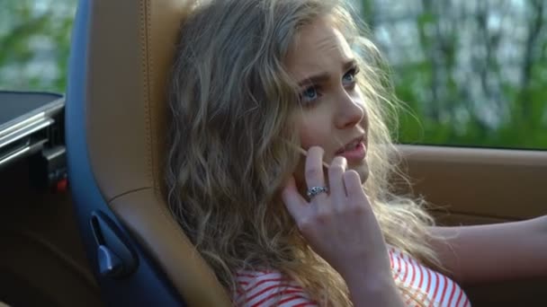 Young pretty blonde woman talking on her phone in her brand-new car with modern inside and leather seats. — Stock Video