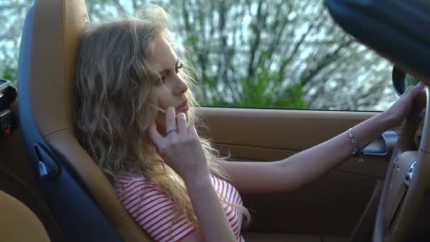Νέοι όμορφη ξανθιά γυναίκα, μιλώντας στο τηλέφωνό της στο αυτοκίνητό της ολοκαίνουργιο μοντέρνο εσωτερικό με δερμάτινα καθίσματα. — Αρχείο Βίντεο
