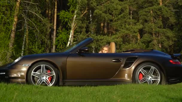 Jonge mooie blonde vrouw praten over haar telefoon in haar gloednieuwe auto met moderne binnen- en lederen zetels. — Stockvideo