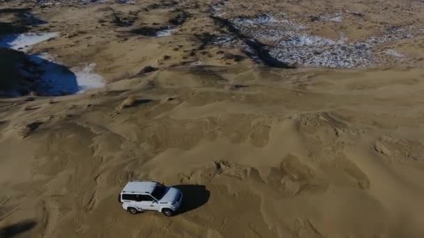 Pemandangan udara suv bergerak melalui gurun yang tertutup salju di musim dingin. Western Kazakhstan, Semenanjung Mangyshlak . — Stok Video
