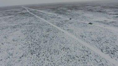 Kış aylarında karla kaplı çölde hareket SUV'lar havadan görünümü. Batı Kazakistan, Mangışlak Yarımadası.