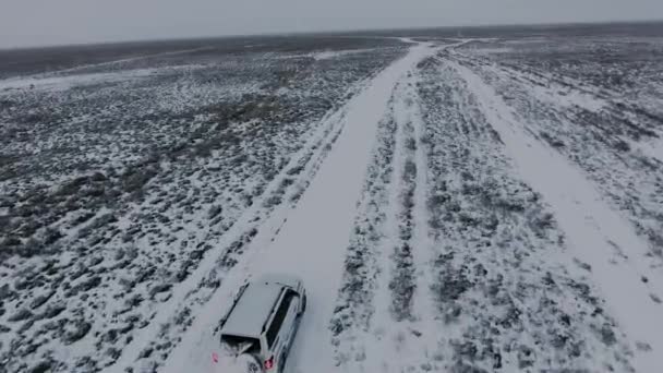 Widok z lotu ptaka z SUV-ów, przenoszenie przez pustynię pokrytych śniegiem zimą. Zachodnim Kazachstanie, półwysep Mangyszłak już. — Wideo stockowe