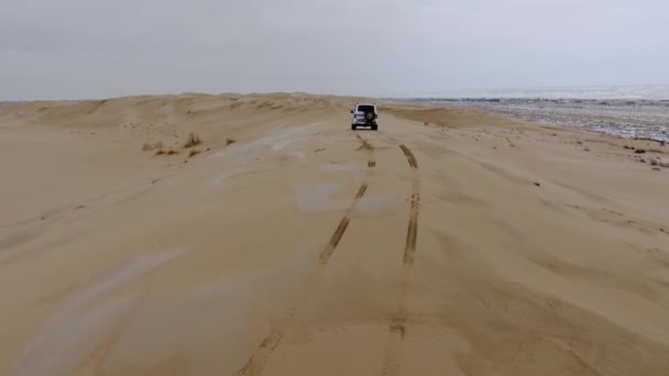 Vista aérea do suv que se move através do deserto coberto de neve no inverno. Cazaquistão Ocidental, Península de Mangyshlak . — Vídeo de Stock