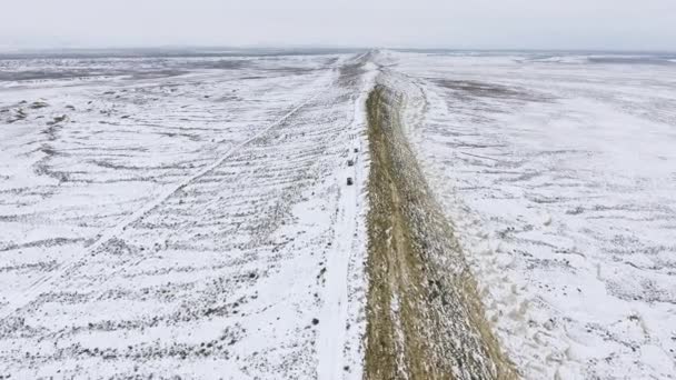 Drei Geländewagen bewegen sich im Winter am Rand einer sandigen Klippe der schneebedeckten Wüste entlang. Westkasachstan, Halbinsel Mangyshlak. — Stockvideo