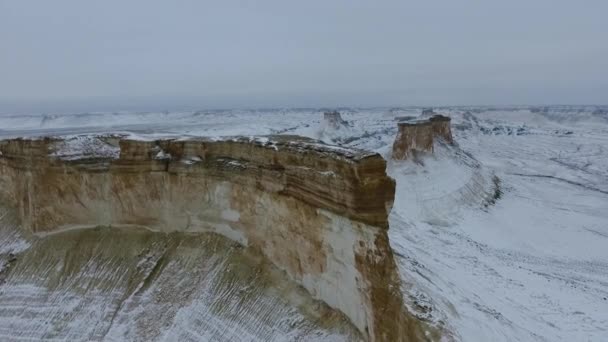 Erstaunliche Luftaufnahme der schneebedeckten Ustyurt sandigen Bergen in Westkasachstan, Halbinsel Mangyshlak. Wüste im Schnee. — Stockvideo